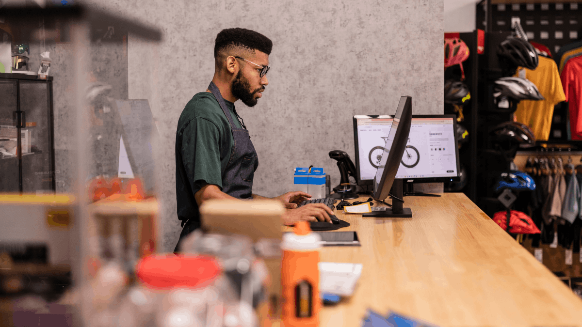 Shop owner processing an order on a computer behind a retail counter